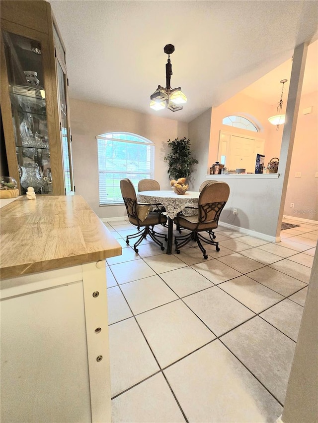 dining area with a notable chandelier, lofted ceiling, and light tile patterned flooring