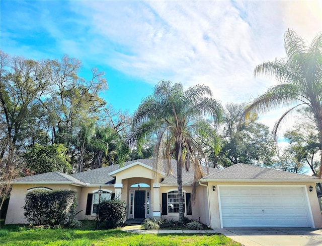 single story home featuring a garage, concrete driveway, roof with shingles, a front lawn, and stucco siding