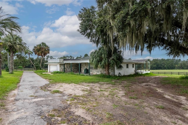 view of front facade with a garage, a rural view, and a front lawn