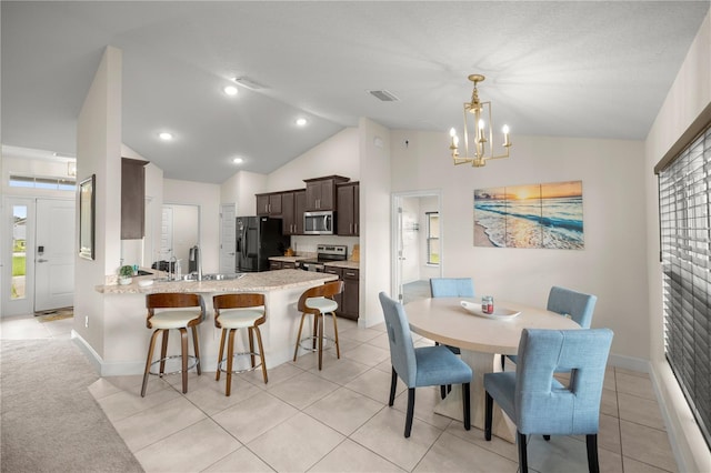 tiled dining room with lofted ceiling, a chandelier, and sink