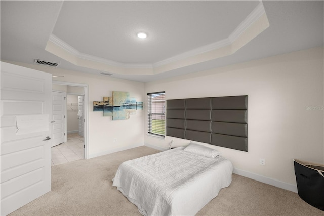 bedroom featuring light colored carpet, ensuite bath, a tray ceiling, and crown molding