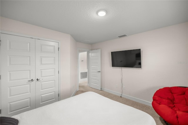 carpeted bedroom with a textured ceiling and a closet