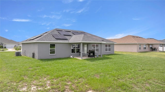 back of property featuring a patio, a yard, and solar panels