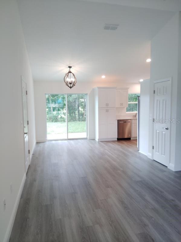 unfurnished living room featuring a chandelier, dark hardwood / wood-style flooring, and a healthy amount of sunlight