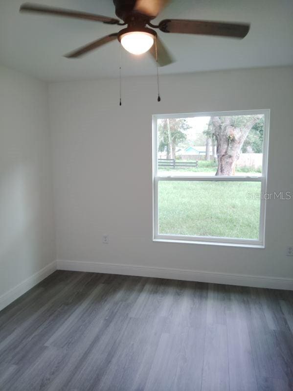 unfurnished room featuring ceiling fan and dark wood-type flooring