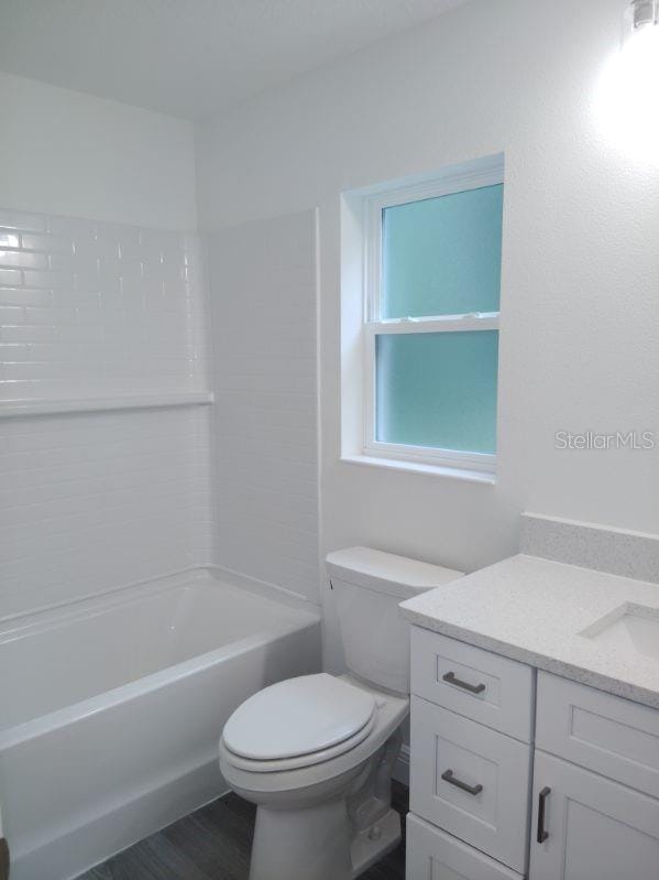 full bathroom featuring shower / bathing tub combination, wood-type flooring, vanity, and toilet