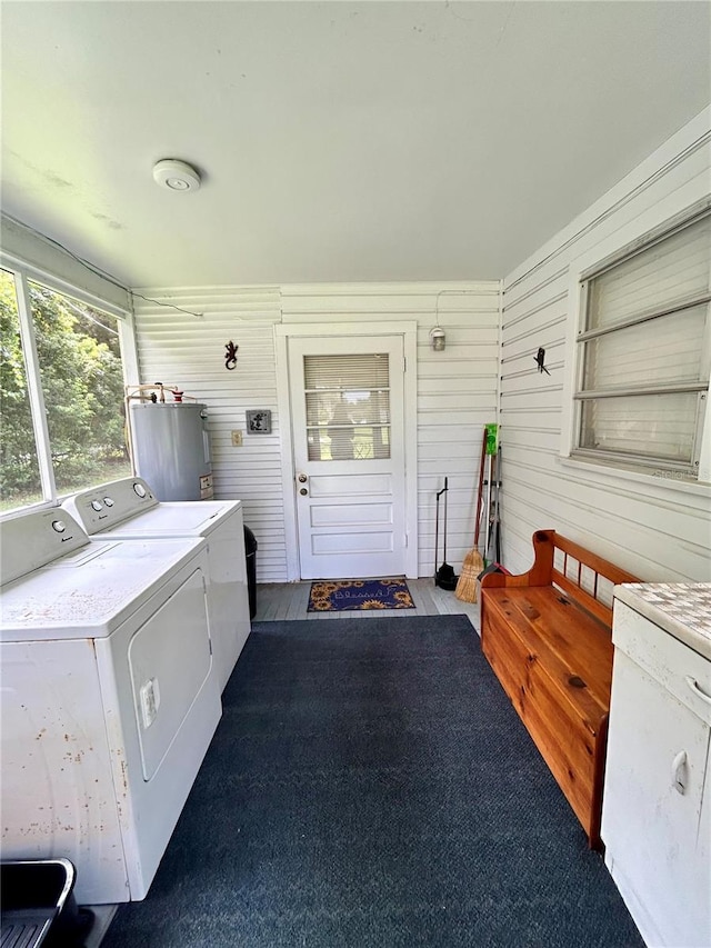 exterior space with carpet floors, wooden walls, washing machine and clothes dryer, and electric water heater