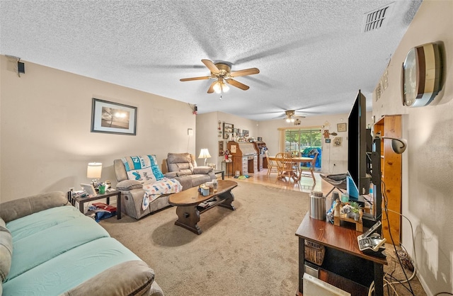 living room with ceiling fan, carpet flooring, and a textured ceiling