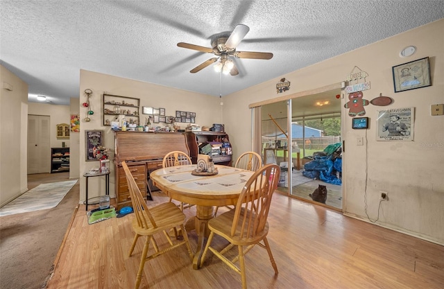 dining area featuring light wood-type flooring, ceiling fan, and a textured ceiling