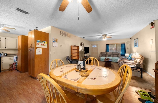 dining space featuring light wood-type flooring, ceiling fan, and a textured ceiling