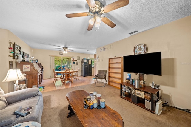 carpeted living room featuring ceiling fan and a textured ceiling