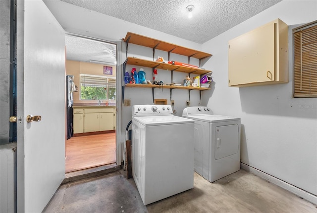 laundry area with a textured ceiling, washing machine and dryer, sink, and cabinets