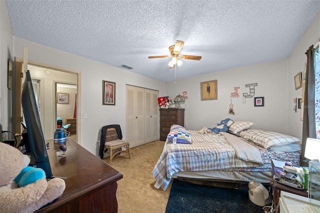 bedroom featuring a textured ceiling, ceiling fan, light colored carpet, and a closet