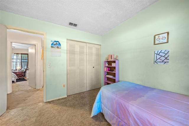 bedroom featuring vaulted ceiling, a closet, light colored carpet, and a textured ceiling