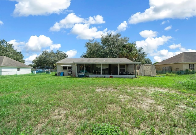 rear view of house featuring a yard, a storage shed, and a sunroom