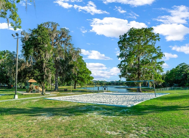 view of community with a lawn, a water view, and volleyball court