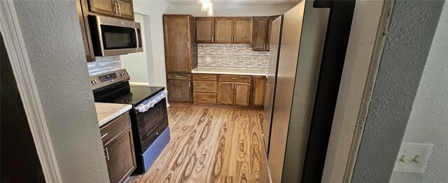 kitchen with black range with electric cooktop, backsplash, and light hardwood / wood-style floors