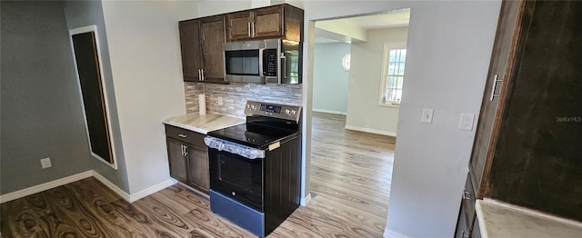 kitchen with dark brown cabinets, light hardwood / wood-style floors, electric range, and tasteful backsplash