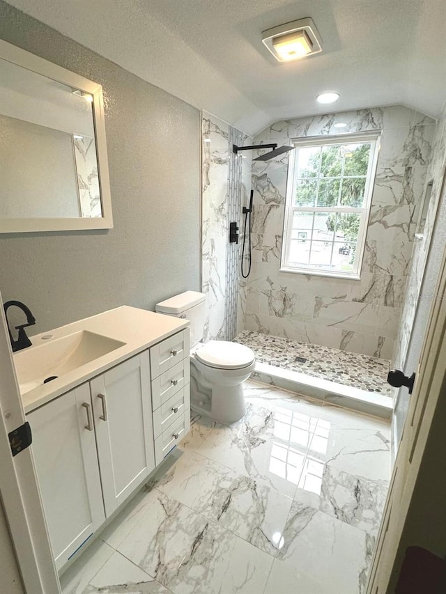 bathroom featuring a textured ceiling, vaulted ceiling, tiled shower, vanity, and toilet