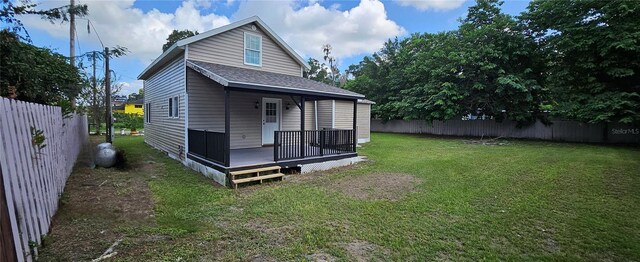 back of house featuring a lawn and a wooden deck