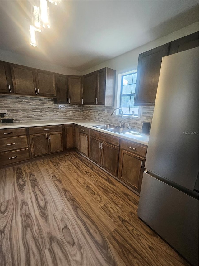 kitchen with dark brown cabinets, hardwood / wood-style flooring, stainless steel fridge, and sink