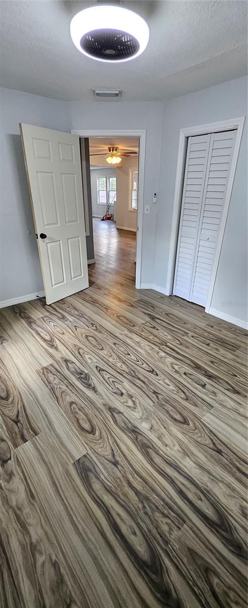 unfurnished bedroom featuring a closet, hardwood / wood-style floors, and a textured ceiling