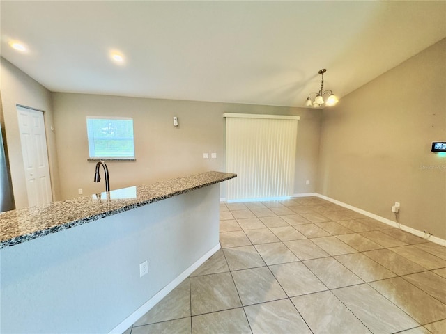 kitchen with stone counters, light tile patterned floors, baseboards, and a chandelier