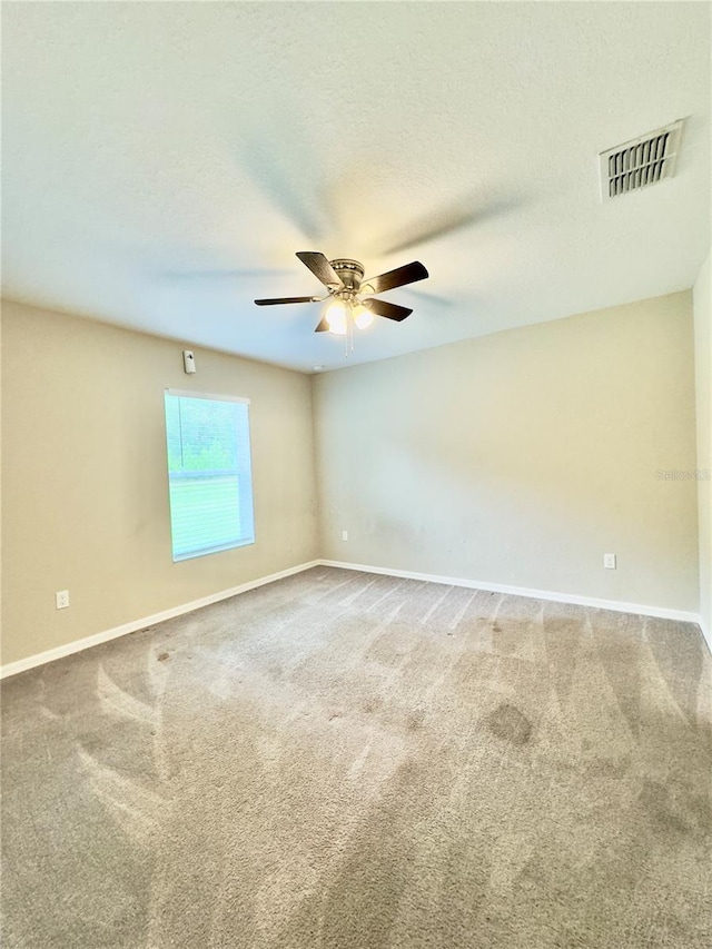 carpeted spare room with ceiling fan and a textured ceiling