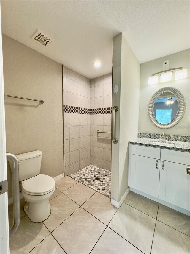 full bathroom with a textured ceiling, visible vents, a tile shower, vanity, and toilet