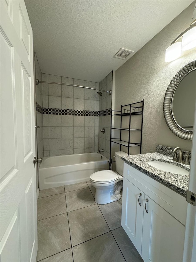 full bathroom featuring tile patterned flooring, a textured ceiling, tiled shower / bath combo, vanity, and toilet