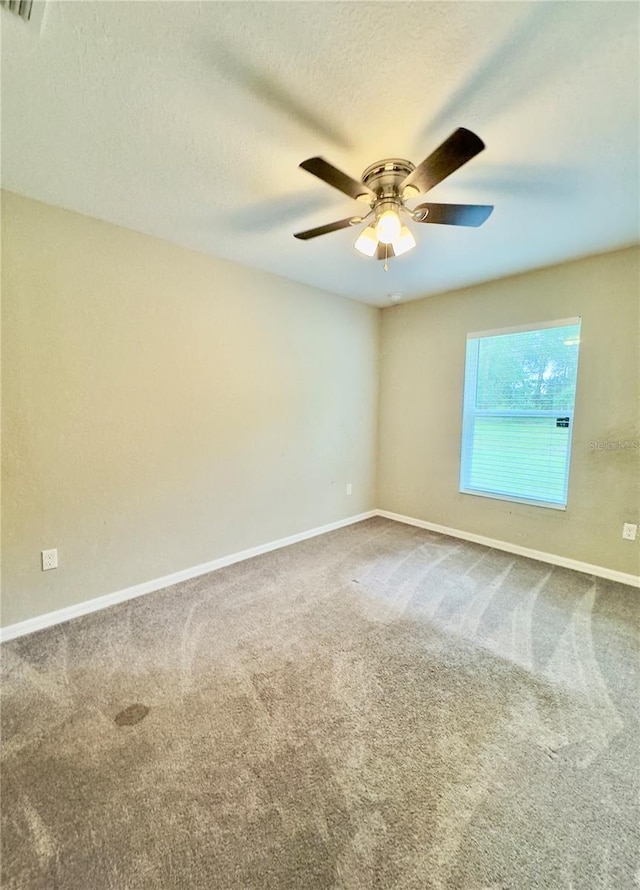 carpeted empty room with a ceiling fan, baseboards, and a textured ceiling