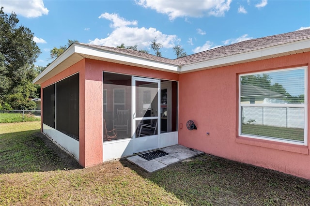 view of side of property featuring a lawn and a sunroom