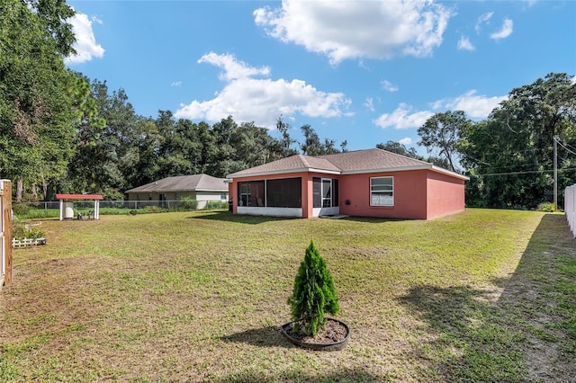 rear view of house featuring a yard and a sunroom