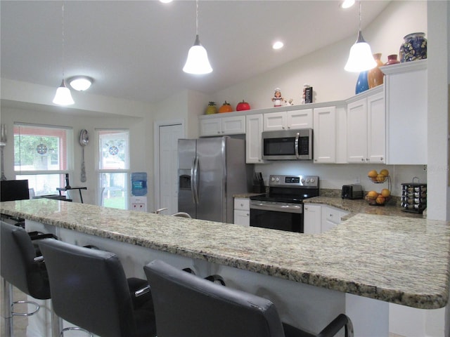 kitchen featuring white cabinets, a kitchen bar, hanging light fixtures, and appliances with stainless steel finishes