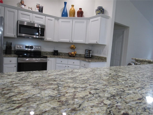 kitchen featuring white cabinetry, stone countertops, and appliances with stainless steel finishes