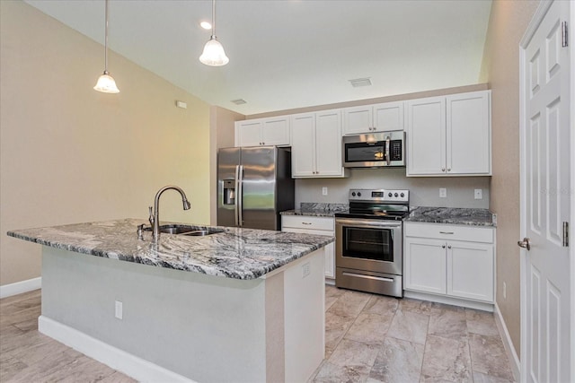 kitchen featuring appliances with stainless steel finishes, sink, hanging light fixtures, white cabinets, and a kitchen island with sink