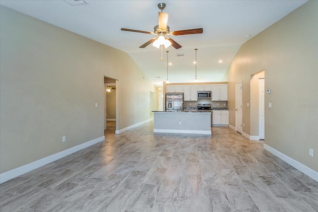 kitchen featuring ceiling fan, stainless steel appliances, lofted ceiling, white cabinets, and a center island with sink