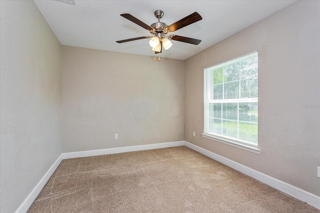 empty room featuring ceiling fan, light carpet, and plenty of natural light