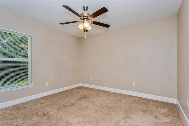 carpeted spare room featuring ceiling fan and a wealth of natural light