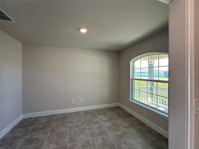 tiled spare room featuring a textured ceiling