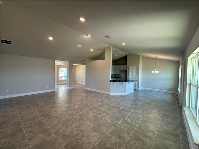 unfurnished living room featuring a notable chandelier, lofted ceiling, sink, and tile patterned floors