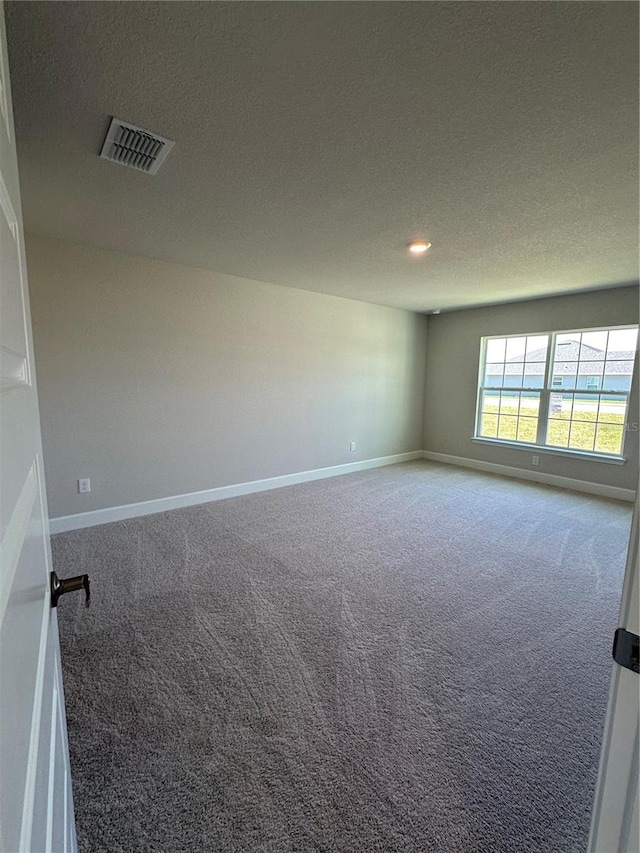 carpeted spare room featuring a textured ceiling