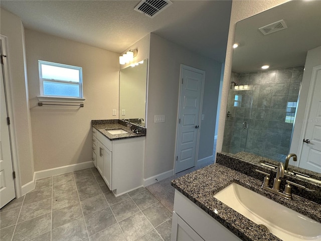 bathroom featuring a textured ceiling, tile patterned flooring, vanity, and a shower with door