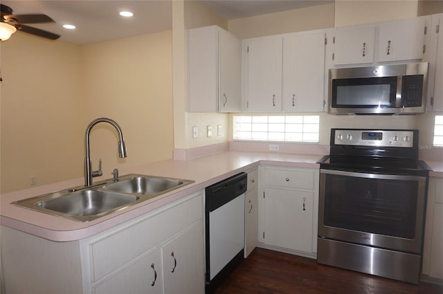 kitchen featuring appliances with stainless steel finishes, white cabinetry, ceiling fan, dark hardwood / wood-style floors, and sink