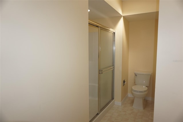 bathroom featuring a shower with shower door and toilet