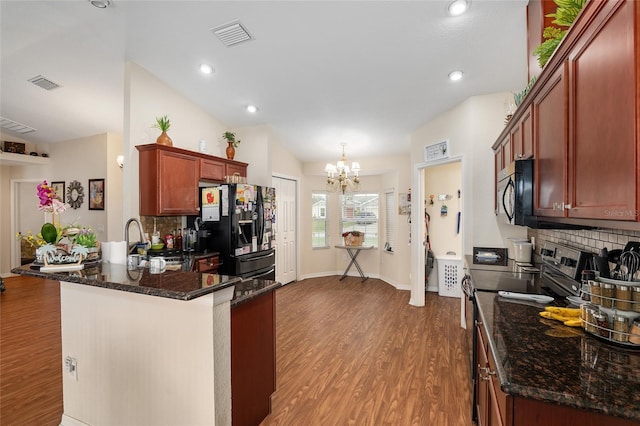 kitchen featuring hardwood / wood-style flooring, dark stone countertops, backsplash, black appliances, and kitchen peninsula