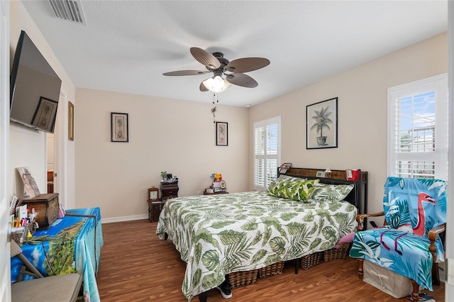 bedroom featuring ceiling fan, hardwood / wood-style floors, and multiple windows