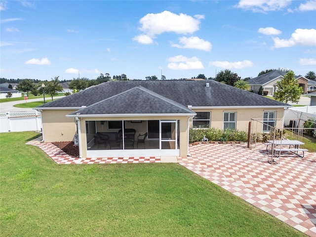 rear view of property with a lawn, a sunroom, and a patio