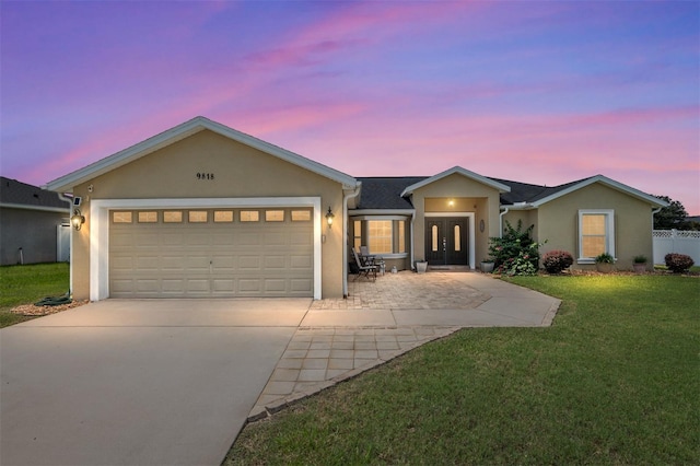 single story home with a garage and a yard