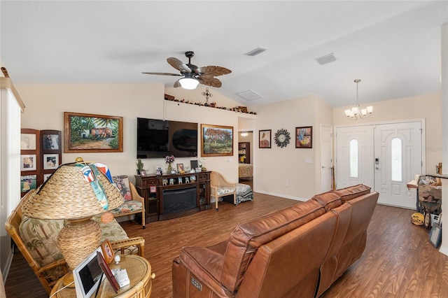 living room featuring dark wood-type flooring, a fireplace, ceiling fan with notable chandelier, and vaulted ceiling